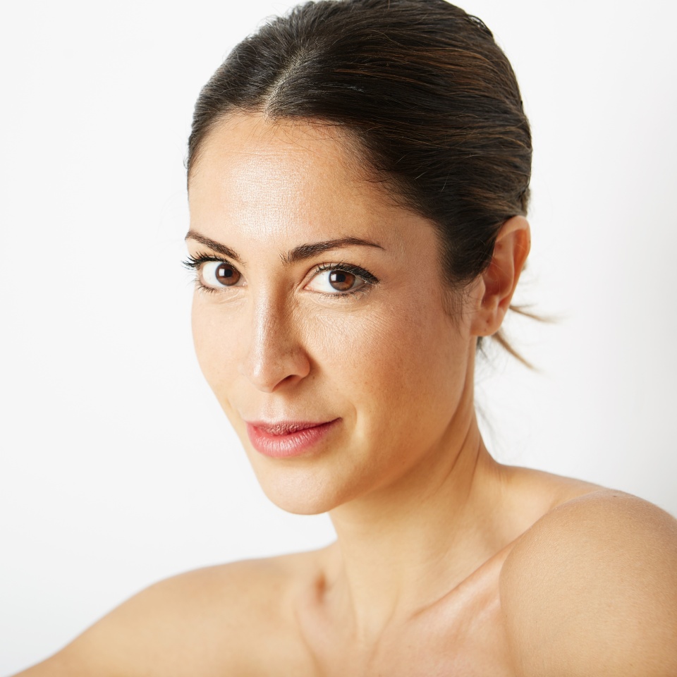 Glamour portrait of beautiful woman model with fresh daily makeup and romantic smile. Fashion shiny highlighter on skin, sexy gloss lips make-up and dark eyebrows. Healthcare skin concept