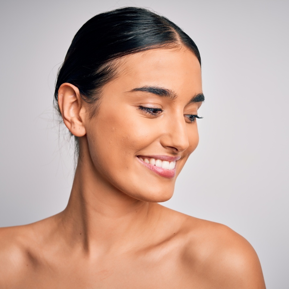 Close up of young beautiful woman with clear and pure skin. Perfect and clean skincare wearing natural makeup. Smiling happy looking fresh and healthy.