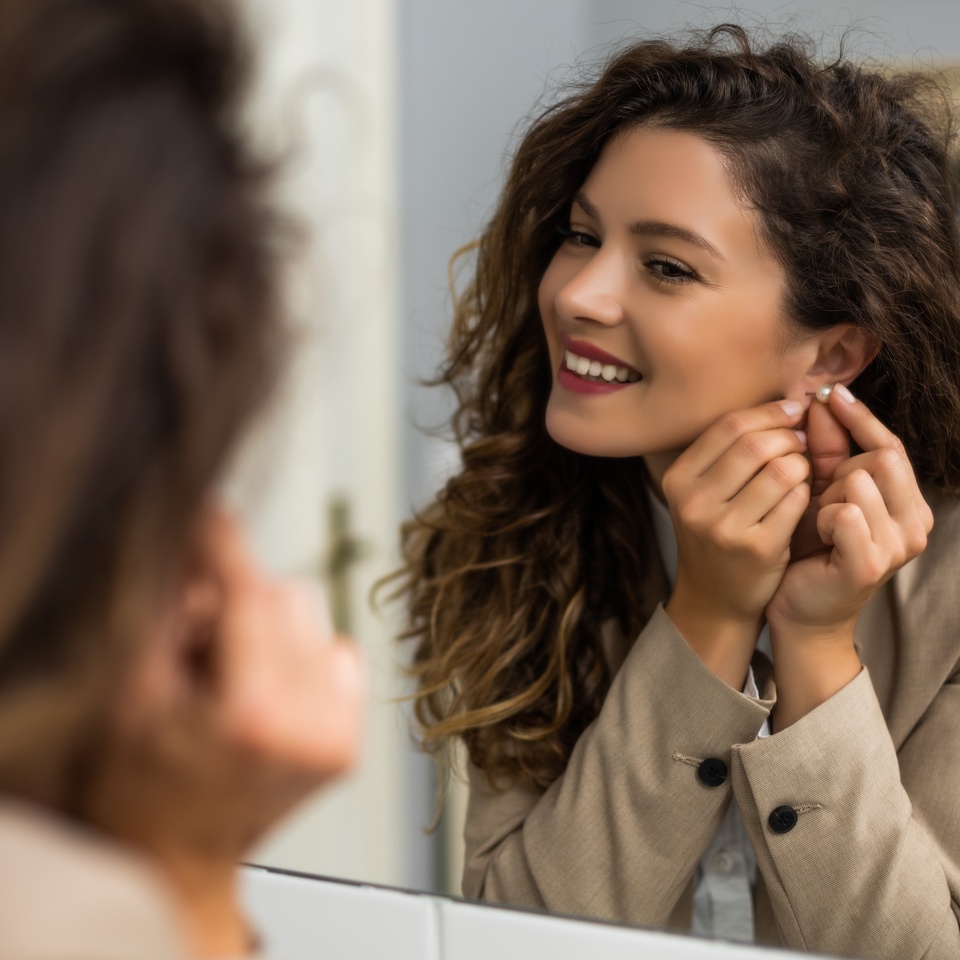 Businesswoman is putting earrings while preparing for work.
