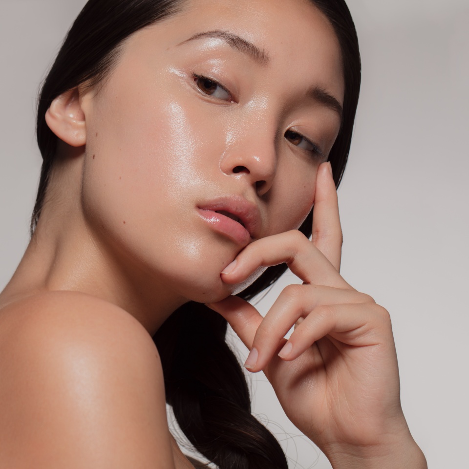 Young asian woman with glowing skin looking away with an attitude. Female with beautiful skin against beige background.