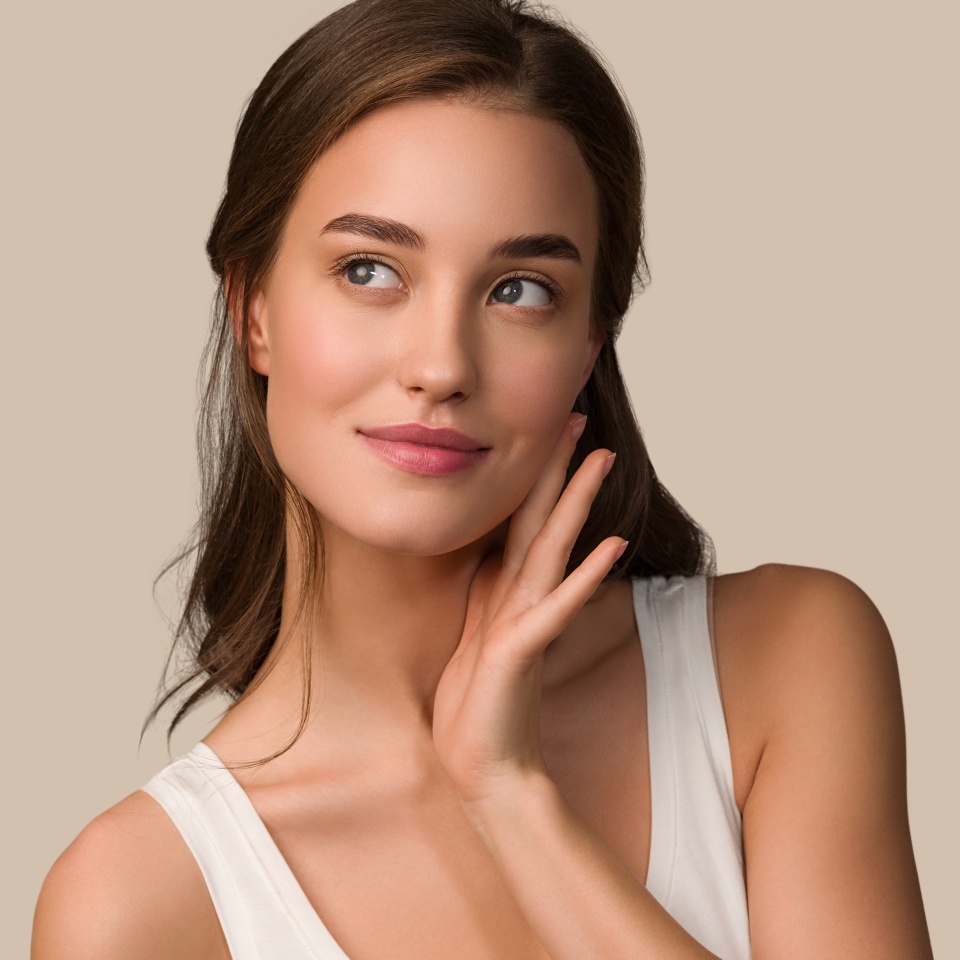 Beauty model woman with healthy natural make up clean skin touching her face Color background brown