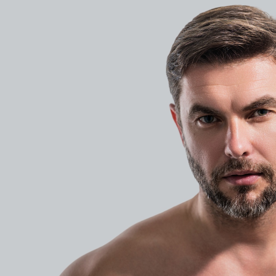 Beauty portrait of man with moisturizing cream on face, isolated background. Skincare routine. Male haircut, mustache and beard. Male beauty. Shaving, hair styling. Banner for header, copy space.