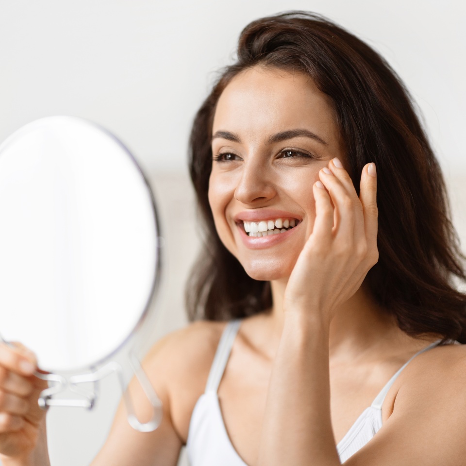 Analytical millennial woman focused on skincare, closely examining her eyes in a bathroom, anti-ageing skin care