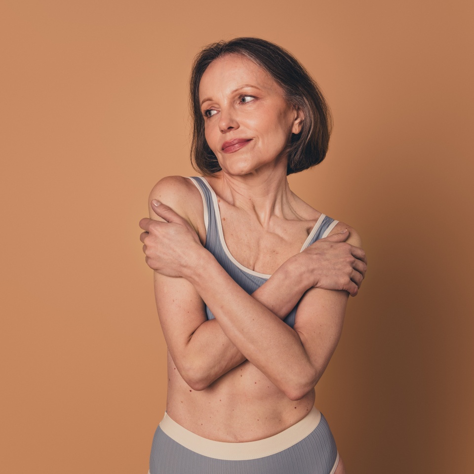 No filter photo of lovely cute senior woman hugging herself empty space isolated on beige color background
