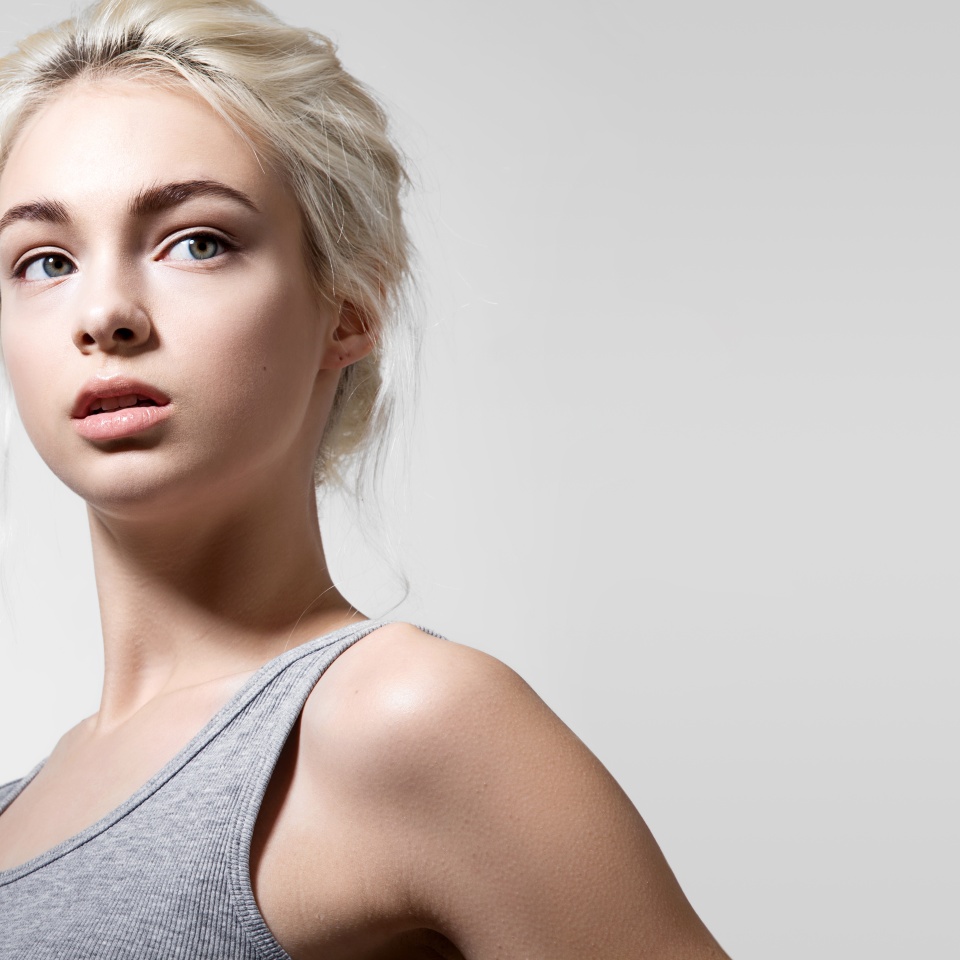 Girl with a good clean skin of the face in a gray shirt on a light background