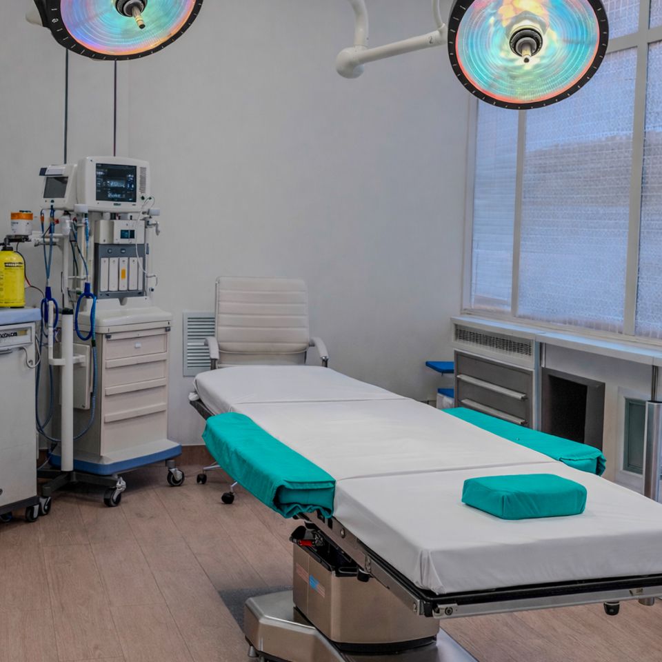 A well-lit, modern operating room with a surgical table, medical equipment, overhead lights and monitors.