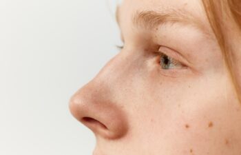 Side view close-up image of male face, eyes and nose. Young redhead model posing over grey studio background. Concept of men's health, body and skin care, hygiene and male cosmetology