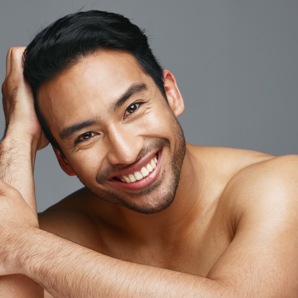 Face, cosmetics and Asian man with skincare, smile and dermatology on a grey studio background. Portrait, Japanese person and happy model with wellness, luxury treatment and beauty with aesthetic